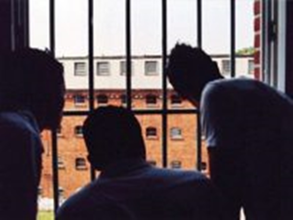 Corona im Gefängnis - drei Inhaftierte vor Gitterstäben